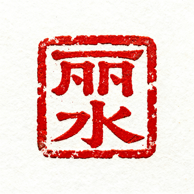 古朴传统的方形印章，印面是篆书“丽水”二字，朱红色印泥，带有自然的磨损质感，边缘有轻微的做旧效果