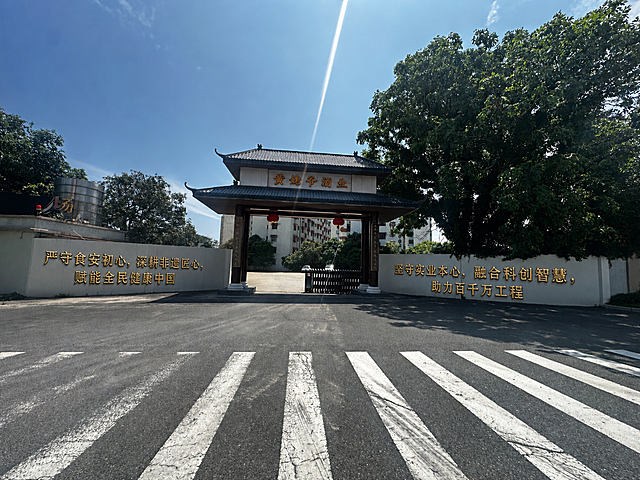 在这张图片中，将文字'严守食安初心，深耕非遗匠心，赋能全民健康中国'以金色浮雕字的形式贴在图片左侧的白色墙上，将文字'坚守实业本心，融合科创智慧，助力百千万工程'以同样的金色浮雕字形式贴在图片右侧的白色墙上，保持原场景的透视和光影效果不变