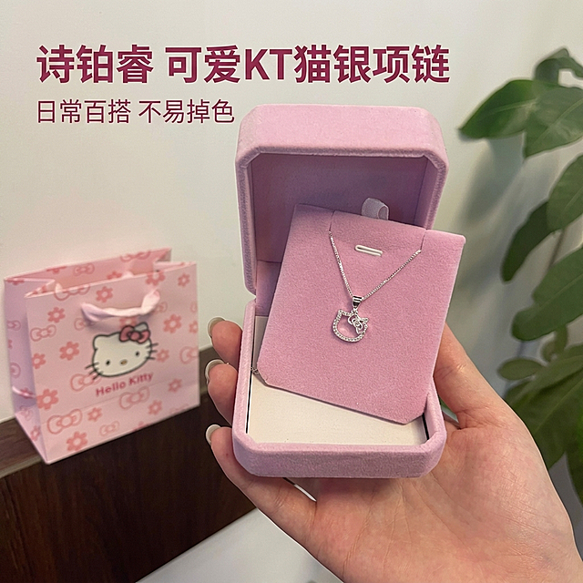 [主图 1] 诗铂睿银色KT猫带坠项链产品展示首图
[氛围风格] 温馨舒适家居治愈风，高级松弛感，生活化自然场景
[画质] 商业摄影质感，光线柔和通透，产品清晰真实，画面干净高级，超高清
[元素] 银色KT猫镂空项链放在粉色绒布首饰盒中，一只手轻轻拿着首饰盒，背景是干净的奶白色墙面，旁边点缀一片绿色龟背竹叶片和粉色Hello Kitty礼品袋，整体画面温馨治愈。保持项链外观（物理结构、材质质感、颜色）与输入产品图绝对一致，杜绝任何变形和色差，精细化处理。商品主体占比严格控制在70%左右，画面满屏无边框。
[光影] 柔和的室内自然光从左侧照射进来，形成柔和的明暗过渡，金属项链高光自然细腻，绒布盒子呈现柔和哑光质感，阴影过渡自然不生硬，整体光线通透不灰蒙
[配色] 主色调：柔粉色、银色；辅助色：奶白色、绿色，整体配色温柔治愈清新
[视角构图] 平视视角，产品位于画面中心，景深适中，背景虚化突出主体，产品轮廓完整无裁切
[文字版式] 左上角负空间左对齐留安全边距，主标题 "诗铂睿 可爱KT猫银项链" 深粉色最大号粗体无衬线字体；副标题 "日常百搭 不易掉色" 约半高，同色系略浅。文字不遮挡产品主体
[比例分辨率] 1:1 比例，2k 分辨率，文字清晰锐利
[负向提示词] 变形，水印，文字错乱，产品图模糊，背景杂乱，牛皮癣，配色刺眼，遮挡主体