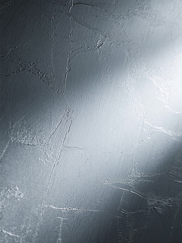 金属纹理背景，呈现出细腻且不规则的蚀刻质感，整体为银灰色调，带有自然的划痕和细微的凹凸纹理，光线从右侧柔和照射，形成从深灰到浅灰的渐变光影效果，表面具有磨砂般的哑光光泽，质感坚硬且带有工业风的冷峻氛围，无任何文字、图案或标识，仅为纯粹的金属材质纹理背景。