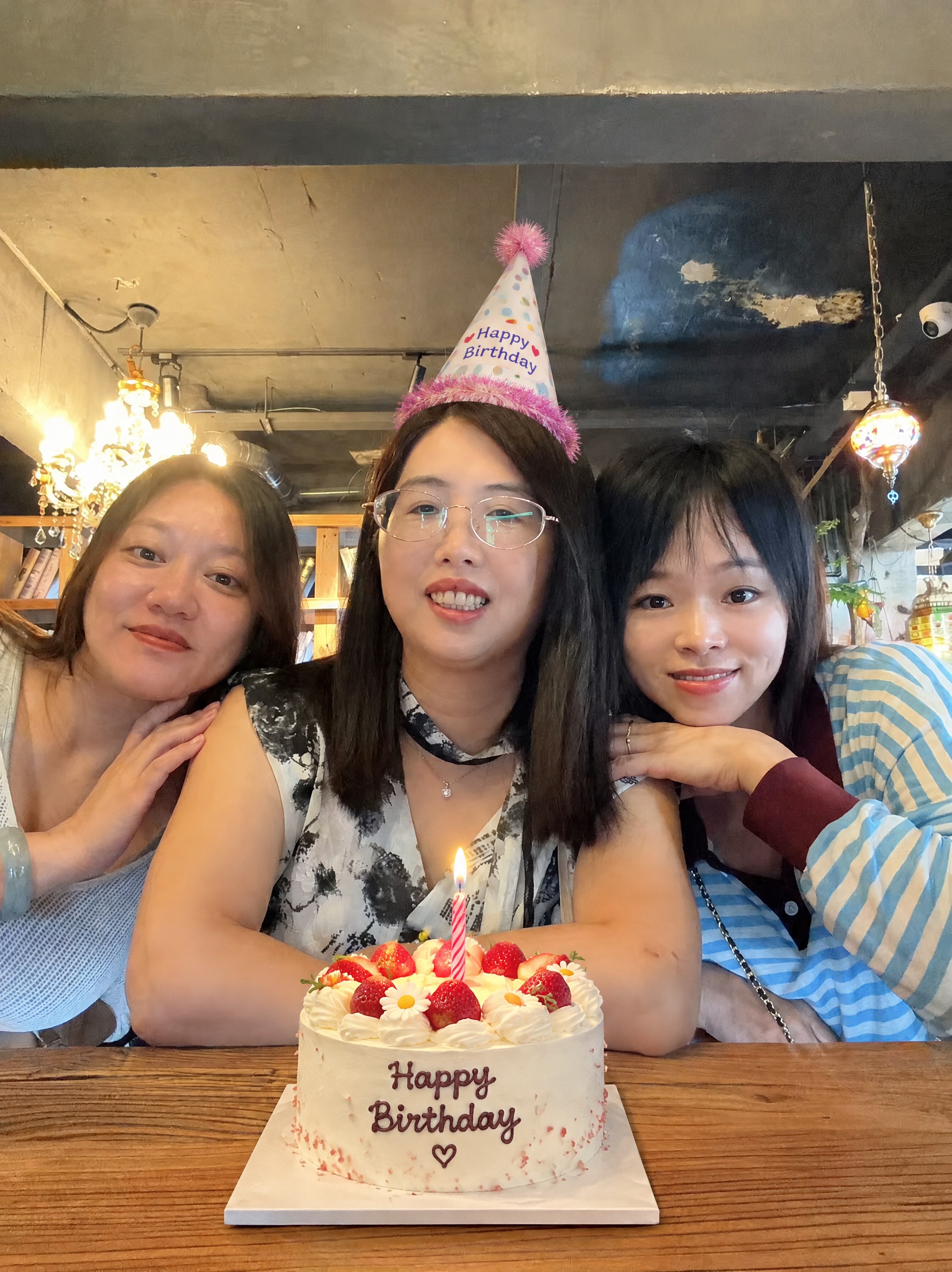 在这张照片中，给中间的女生头上加一个合适的生日帽，生日帽不要带… - 图片创意预览