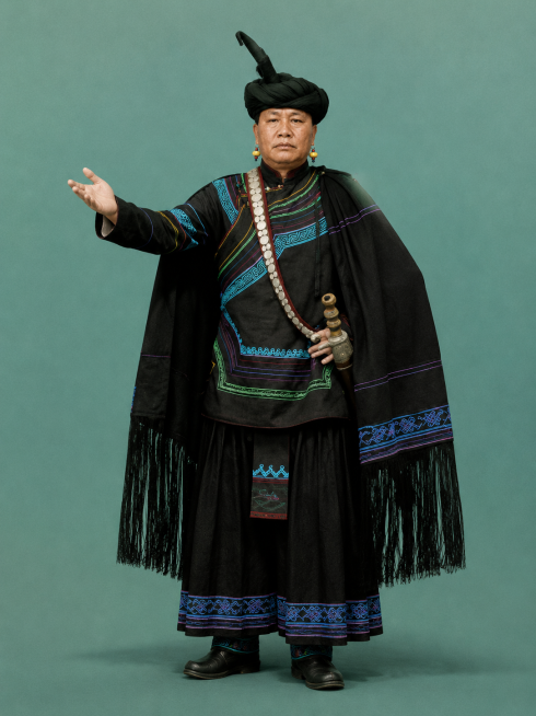 将人物改为全身照，参考图样式添加彝族传统佩刀，保持人物容貌，搭配完整古彝人头人服饰，背景保持简洁预览效果