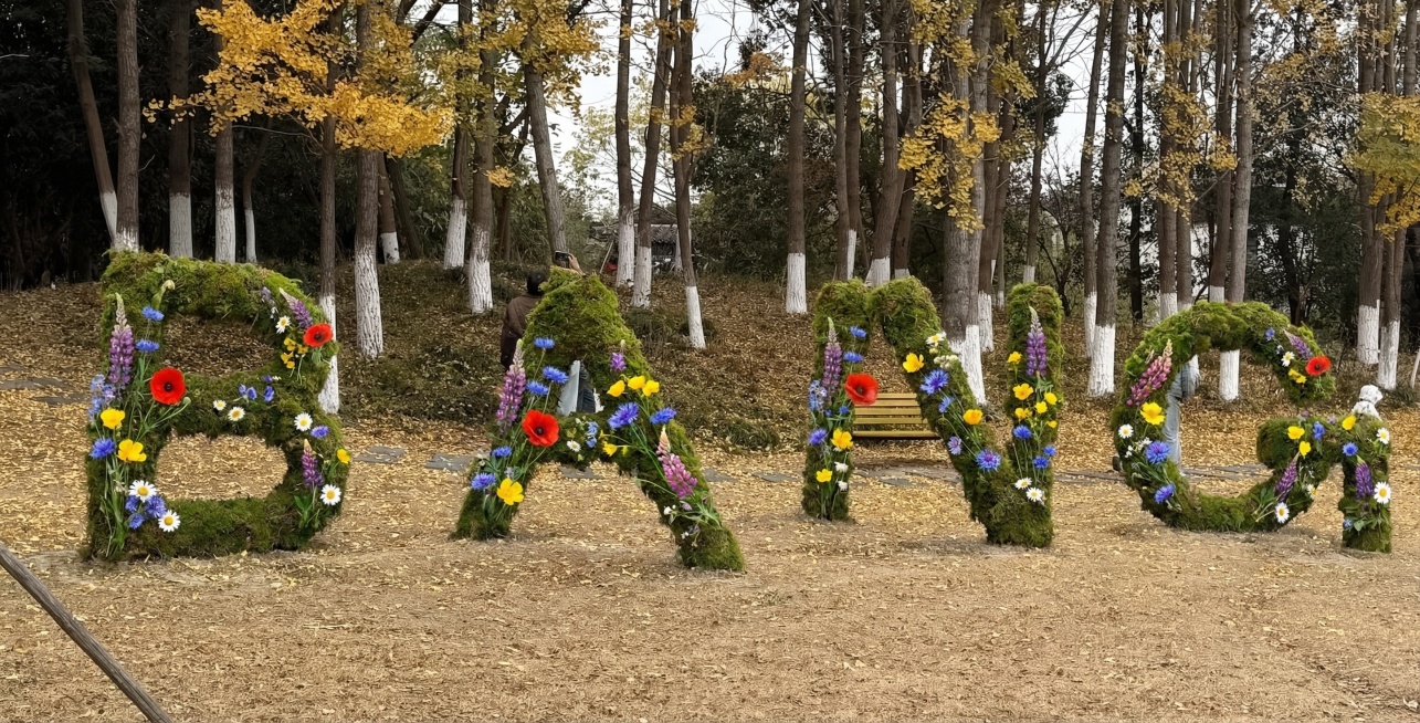 将图1中的稻草字母替换为覆盖绿色苔藓，装饰上多种色彩的野花，风格参考图2和图3预览效果