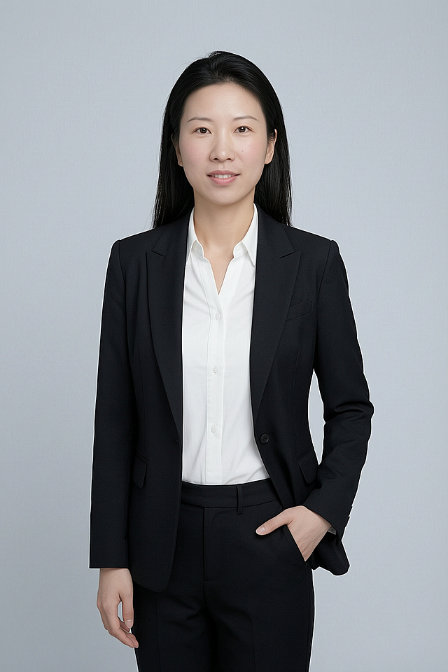 基于参考图生成一张形象照，人物身穿黑色亚面精纺面料西装外套和黑色亚面精纺面料西裤，内搭白色衬衫，背景是简约冷调浅灰色纯色背景，背景光线均匀柔和，呈现均匀柔和质感，极简干净，强化色彩对比的高级感，采用标准焦段50mm,F/4光圈，平视视角，人物占画面70%，人物居中构图，位于画面中心，为视觉聚焦点，入境范围为头部及以下至臀部下方10cm，半身像构图，人物呈正面单手插兜姿态，左手插在西装裤侧缝口袋，仅露出手腕部分，右臂自然垂落，肢体自然，自信从容