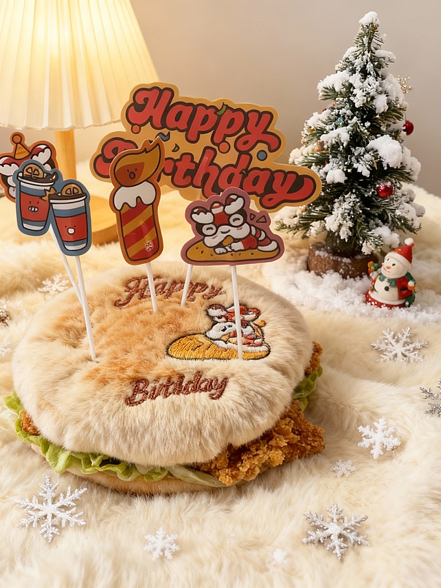 插画风毛绒汉堡生日蛋糕，融合刺绣风与轻拟物设计，搭配卡通蜡烛与雪景圣诞树，营造可爱、喜庆又温馨的节日氛围。