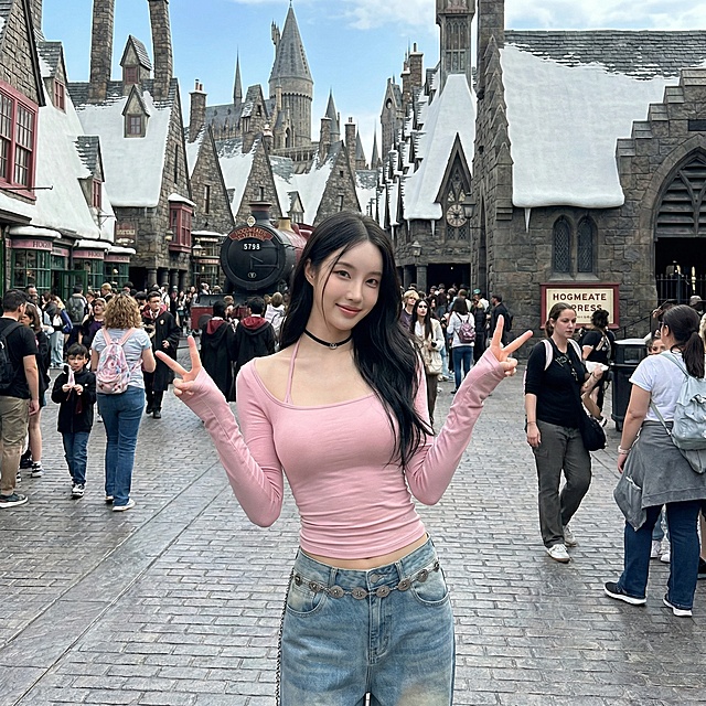 将背景替换为环球影城内部场景，保持模特和衣服不变，更换为双手比耶的姿势