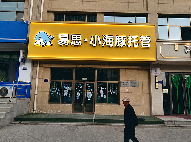 修改门头，将文字改为白字黑边的立体精工发光字，发暖光；门头仅上下边凸出20公分，内嵌灯带发暖光，左右不凸出，有质感，发光自然，保留小海豚logo和易思·小海豚托管文案，保留整体门头黄色背景