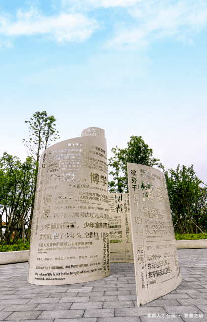 参考原图风格，将地面修改为灰色石砖地面，保留文字雕塑装置、树木蓝天等其他内容不变预览效果