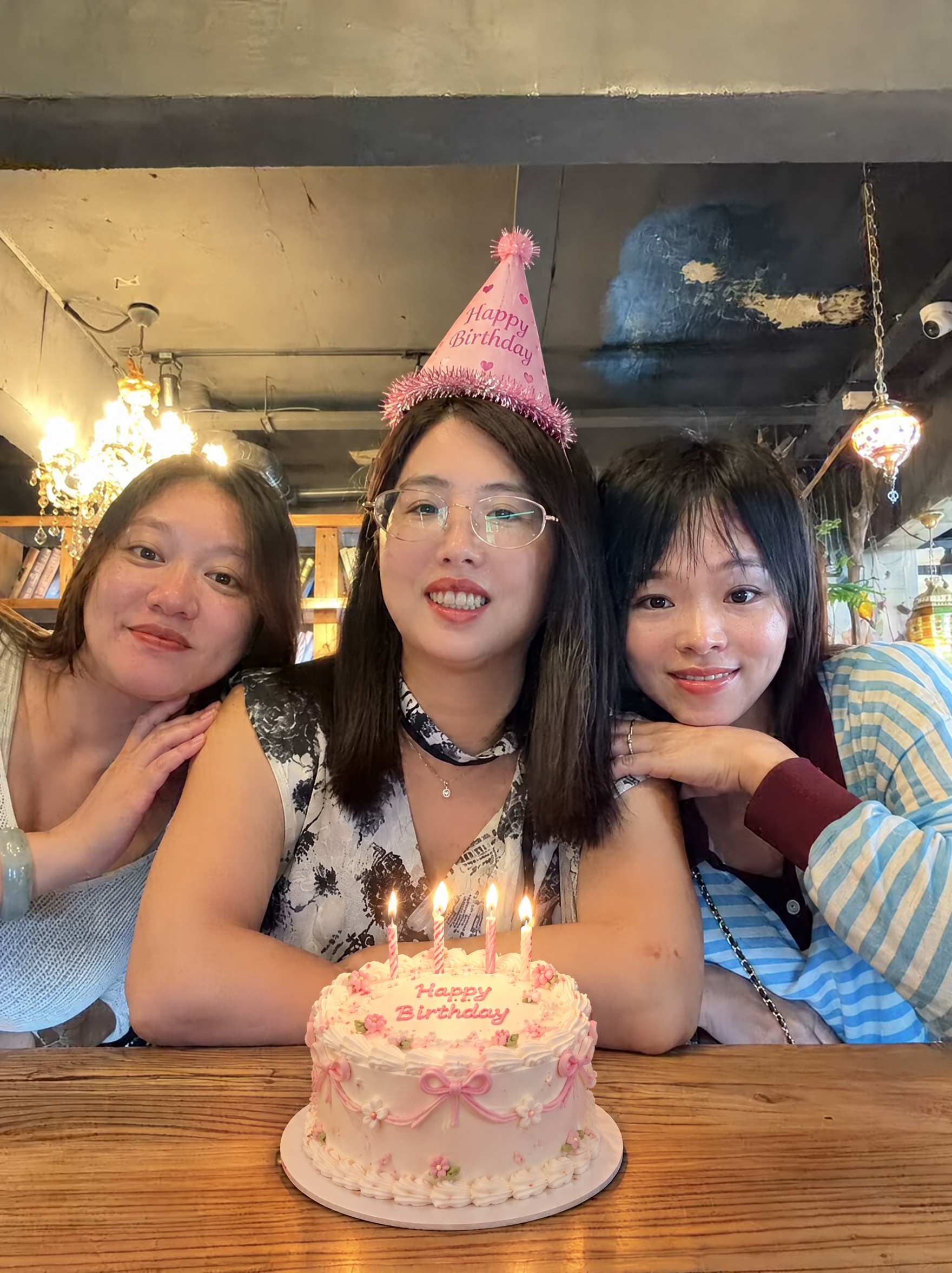 在这张照片中，给中间的女生头上戴一个合适的粉色生日帽，在桌子中… - 图片创意预览