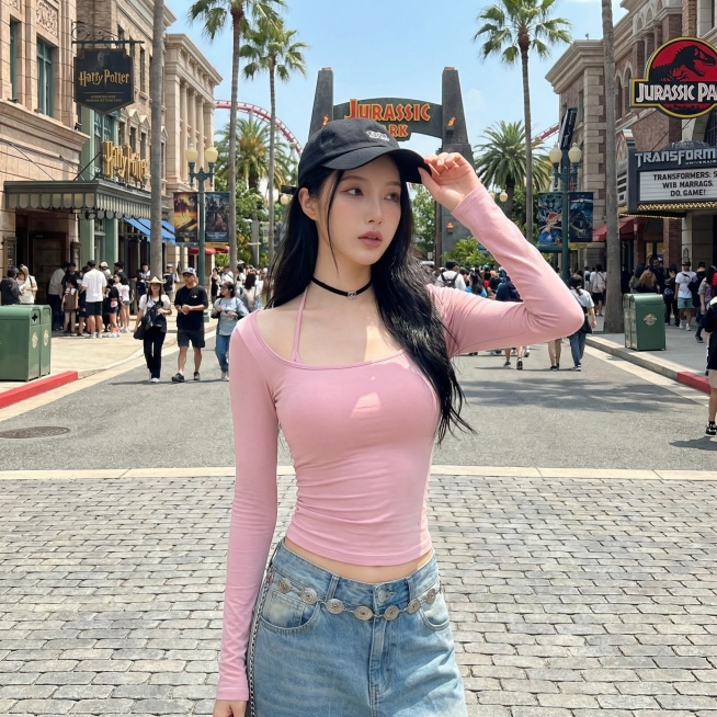 将背景替换为环球影城内部场景，保持模特和衣服不变，更换为单手扶帽的姿势预览效果