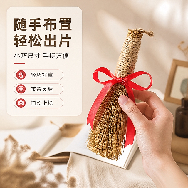 [商品] 使用【图2】稻草小毛刷捆红绳（手持款）；保留稻草材质、麻绳手柄、红绳蝴蝶结、手部持握姿态与真实比例；商品处理：保留手部自然持握状态，增强稻草与红绳质感，不改变商品外形颜色。
[画面] 页面目标：手持使用瞬间，体现小毛刷作为摄影道具的手持布置感与使用代入感；构图：右下主体（手+毛刷），左上文字区；景别：中近景；阅读动线：左上主标题与卖点，右下手持毛刷主体；动作：一只手自然捏住小毛刷麻绳手柄处，呈布置拍摄道具的动态感；背景：浅暖米色虚化桌面场景，柔和自然光，营造轻松的拍摄准备氛围。
[视觉] 套系策略：风格=质朴复古静物摄影风，暖调质感商业详情页；标题字=阿里巴巴普惠体粗体；正文字=阿里巴巴普惠体常规；主色=暖米杏；背景延展=基于暖米杏做深浅层级、同色渐变和细腻纸张/麻布质感；强调色=正红色，仅用于小面积标签、引线和重点文字高亮；标题色=深棕褐；正文色=中暖灰；组件=圆角浅底信息卡、细线引线、圆点装饰；光影=左前侧暖柔光，柔和阴影。
[文字] 主标题：随手布置 轻松出片；副标题：小巧尺寸 手持方便；3个短卖点：轻巧好拿、布置灵活、拍照上镜；文字区位于左上圆角信息卡，所有文字横排，不遮挡手部与毛刷主体。
[规格] 图片比例1:1正方形，4K分辨率，负向提示：避免变形、错字、文字过小、冷蓝/蓝灰背景、极限词（天然/环保/原生态/最好/第一）、淘宝平台违禁词、小标致图案、竖排文字、二维码、水印。