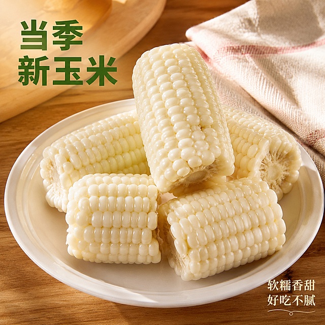 [主图-4] 白糯玉米餐桌场景展示，增强生活代入感。[氛围风格] 温馨生活场景，增强食欲和购买联想。[画质] 商业摄影质感，光线柔和通透，产品清晰真实，画面干净高级。[元素] 保持白糯玉米外观、颜色与输入产品图绝对一致，杜绝任何变形和色差，精细化处理。煮熟的白糯玉米切段摆放在白色陶瓷餐盘里，摆放自然，颗粒饱满。搭配简单木质餐桌背景，旁边放一张餐巾，生活气息浓厚。玉米主体占比约65%。[光影] 暖色调室内自然光，温馨柔和，突出玉米软糯质感，让人产生食用欲望。[配色] 暖木色+白色+玉米珍珠白，温馨自然。[视角构图] 平视略带俯视，餐盘居中摆放，景深适中。[文字版式] 画面左上角“当季新玉米”深绿色大字，右下角小字“软糯香甜 好吃不腻”，大小对比清晰，不遮挡玉米主体。[输出要求] 1:1比例，文字清晰可辨，超高清商业摄影质感。[负向提示词] 变形，文字错乱，产品图模糊，背景杂乱，水印，电商平台Logo，绝对化违禁词。
