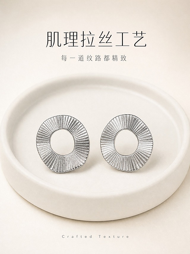 [主图-2] 银色肌理圆环耳钉 核心亮点 材质与工艺展示。
[统一基调] 高级冷银轻奢风格，奶油米白渐变背景，柔光箱高光+窄条轮廓光体现金属质感，标题字色深炭灰，辅助字色中暖灰，强调色冷银白，字体为现代纤细无衬线体，整体克制精致。
[画面] 静物陈列，一对银色肌理圆环耳钉平放在奶白色哑光陶瓷托盘上，左右对称摆放，主体占比约50%，居中构图。耳钉正面朝上，完整展示不规则圆环造型和放射状拉丝肌理，金属表面有细腻光泽。托盘边缘有柔和阴影，背景为纯净奶油米白渐变，无多余杂物。
[光影质感] 顶部柔光箱均匀布光，耳钉边缘有清晰轮廓光勾勒，拉丝纹理在光线下呈现丰富的明暗层次，金属质感真实厚重，陶瓷托盘有细腻哑光质感，接触阴影自然柔和。
[配色] 背景奶油米白，耳钉冷银色，托盘奶白色，文字深炭灰。
[文字版式] 画面上方居中两行文案，主标题"肌理拉丝工艺"字号较大，副标题"每一道纹路都精致"字号缩小50%以上，底部小号英文"Crafted Texture"装饰，文字均不遮挡耳钉主体。
[输出要求] 比例3:4竖版，2K高清，耳钉细节清晰，金属拉丝纹理锐利。负向：变形、错字、模糊、杂乱、水印、平台Logo、划痕、指纹、灰尘。