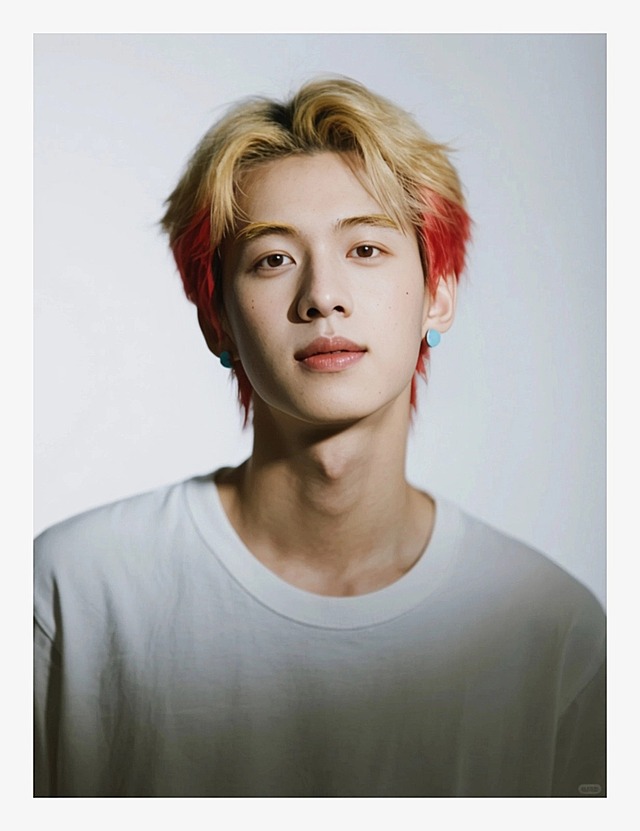 一个男生，狼尾短发，上半部分金色+下半部分嫣红色；金色眉毛；戴浅蓝色耳钉，穿白色T恤