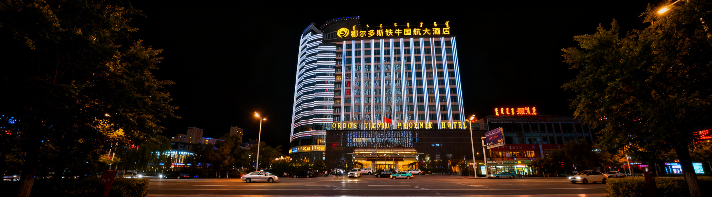 将这张鄂尔多斯铁牛国航大酒店夜景图片整体压缩适配到360*100像素画布，保留完整酒店建筑和顶部发光酒店名称文字，横版构图，保持原有清晰画质和城市夜景灯光氛围预览效果