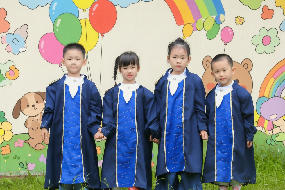 将背景更换为带有幼儿园风格卡通元素的童趣背景墙，保留四个孩子和前景草地不变预览效果