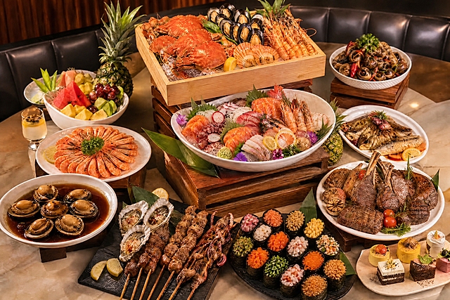将这张自助餐图中的普通寿司全部替换成军舰寿司：海苔围成椭圆形围边、米饭在内、顶部堆满配料的军舰寿司，配料包括橙色鱼籽蟹子、八爪鱼粒、螺肉、海草、吞拿鱼、蟹柳、玉米粒、肉松等，样式参考第二张参考图中黑色盘子里的军舰寿司。只修改寿司部分的形态与摆放，保持餐台整体构图、其他菜品、光线氛围和画质不变，画面干净高级，不添加任何文字。