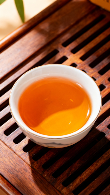 拼多多金骏眉竖版详情页，展示金骏眉冲泡后茶汤，瓷杯盛放橙黄透亮的金骏眉茶汤，木质茶盘背景，暖调自然光，突出茶汤通透，9:16竖版预览效果