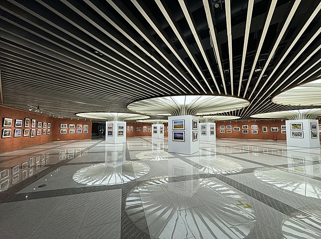 布置成一个公共艺术空间，周围展示着各类摄影作品，在圆柱子周围包裹起一个方形的造型，用于布置和悬挂作品。