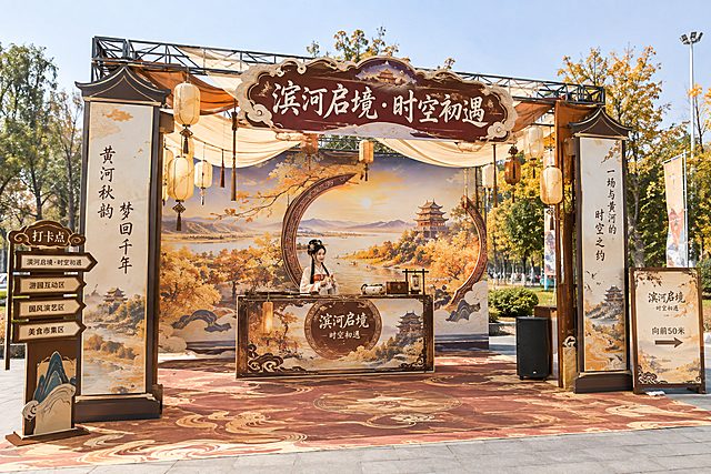 第一站滨河启境打卡点美陈效果图，古风沉浸式游园会风格，桁架搭建+KT板喷绘结构，主背景为大型喷绘画面展现黄河滨河秋景与古风时空之门意境，顶部桁架悬挂古风灯笼与纱幔装饰，正面KT板大字标题"滨河启境·时空初遇"，两侧立有古风立柱造型KT板，前方设古风NPC互动台，整体色调以金秋暖黄+古铜色为主，国潮古风设计，户外游园场景，地面铺古风地毯，两侧有引导指示牌，无复杂木工造型，全部为桁架和KT板喷绘材质，真实活动搭建效果，白天自然光，高清细节