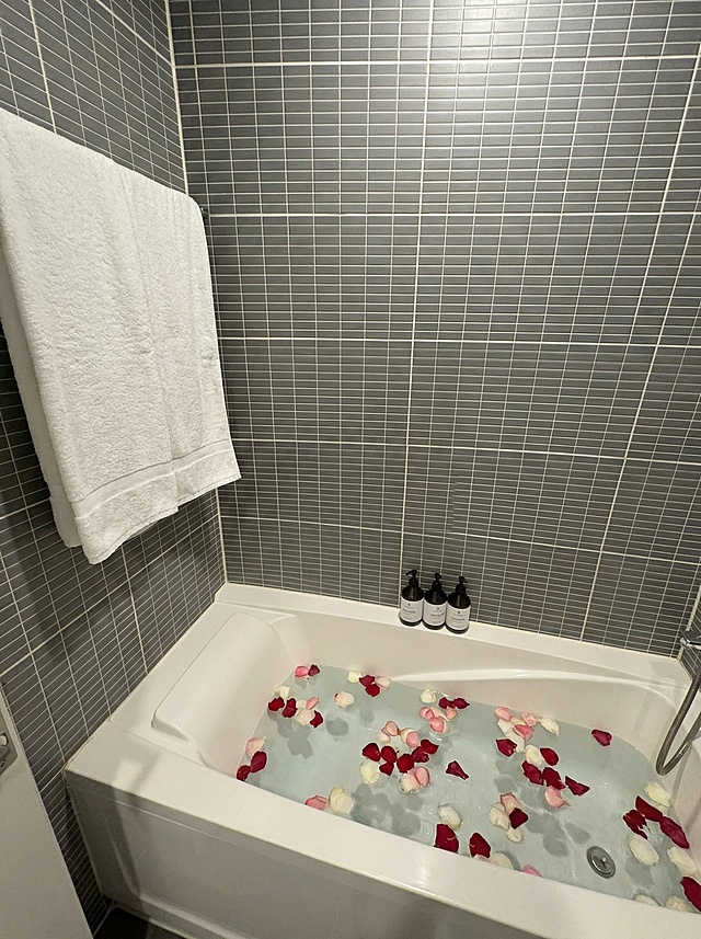 在墙上添加一条挂着的浴巾，浴缸中加入水和散落的花瓣