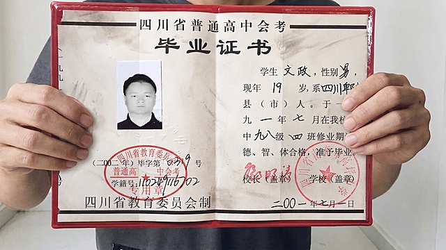 请将参考图1的【四川省普通高中会考毕业证书（红色封皮翻开状态）】1:1 还原其形态、文字、印章、黑白照片、红色封皮、细节纹理、污渍质感等所有细节，替换掉参考图2模特手中的中等职业学校毕业证书，保持参考图2中双手持握证书的姿势、手指位置、抓握角度完全不变；完全保持参考图2模特的身姿、面部、发型、气质、动作/姿态不变（含手部位置、朝向、重心、肩线）；模特身上参考图1未覆盖的部位（深灰色T恤、裤子）严格保持参考图2原样；画面背景、光影、构图、景别严格保持参考图2原样，不做改写。

参考图1的毕业证书1:1还原所有细节；尺寸贴合双手持握比例，证书正面朝向镜头，自然展开，角度和透视与参考图2中原证书完全一致。

超写实高清画质，细节层次丰富，色彩还原真实，整体质感自然真实；商业摄影写实质感。

毕业证书持握位置合理；双手与证书自然接触，手指抓握证书边缘姿态自然；入画部位人体结构正确（手指数量正确、关节自然、手腕线条柔和）；证书与手部接触处有自然接触阴影与压痕；证书与人体边界清晰可分、层次分明、接触点自然贴合。
