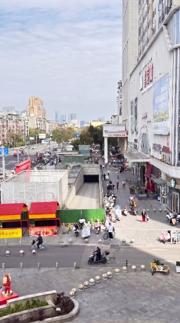 去除围挡左侧地面的台阶结构，改为直接下沉50厘米的斜坡或平滑过渡面，与购物中心地面形成50厘米高差，保持整体街景真实感与光照一致，不出现突兀断层预览效果