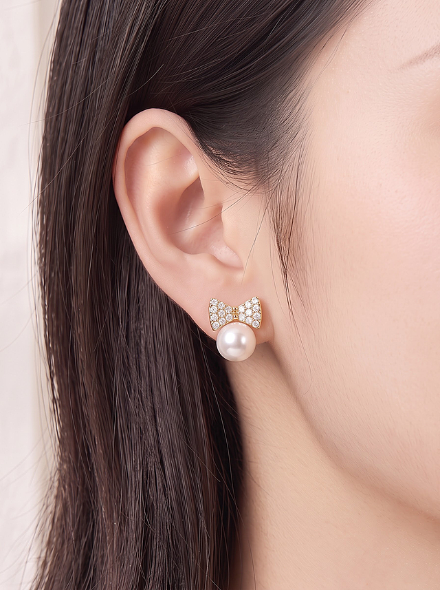 将图1的蝴蝶结珍珠耳钉（珍珠直径6mm比例）佩戴到图2模特的耳朵上，替换掉模特耳朵上原有的耳钉。耳钉的蝴蝶结造型、镶钻细节、珍珠质感完全保持不变，佩戴位置自然真实，光影与模特原图保持一致，整体融合自然