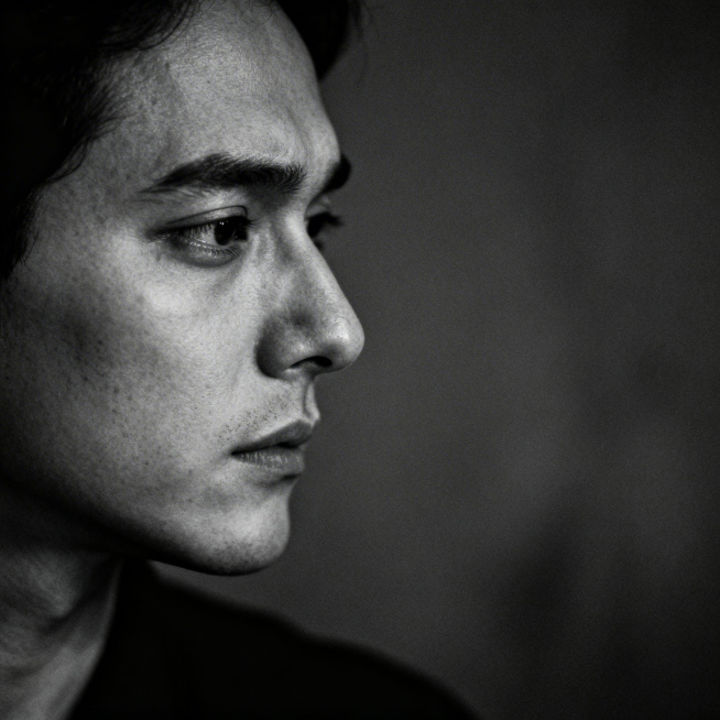 压抑氛围下人物侧脸，黑白低饱和度色调，人物强装镇定，眼神暗藏情绪，体现假装坚强的感觉，画面安静沉重，光影对比柔和，无任何文字预览效果