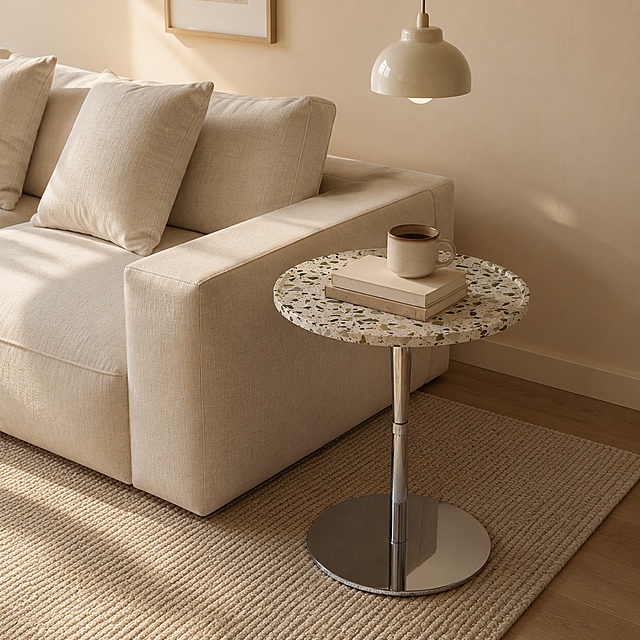 边几严格参照上传产品图https://gdesign-dam-hz.dancf.com/37282319041289306/de05d337dd7141a18d365ccccaf4eec1.jpg，完整保留所有可见组件、部件、轮廓、结构、比例、材质、颜色与产品本体上的文字信息，与上传图完全一致；自然融入场景光影，与场景共处同一物理空间。
室内家居客厅一角，温馨奶咖暖色调。
圆形边几放置在沙发旁，桌子上摆放书籍和杯子，明亮室内阳光照射。
柔和漫射侧光，还原参考图自然光方向，产品受光面泛起奶咖暖色、暗部映射沙发米色光晕，与环境物理融合。
中景居中偏右，微侧 25°视角。
全量换款清单：①沙发：参考图米白灯芯绒布艺直排→生成图米白色棉麻布艺直排沙发；②灯具：参考图悬挂原木壁灯→生成图悬挂奶白陶瓷吊灯；③地面：参考图灰色编织地毯→生成图米色编织地毯；④墙面：参考图浅奶咖乳胶漆墙面→生成图浅暖米色乳胶漆墙面；⑤桌面物品：参考图木质边几上放陶瓷马克杯+杂志收纳→生成图水磨石圆桌上放陶瓷咖啡杯+两本书籍。
消除品牌文字。
严格锁定宽高比为1:1。