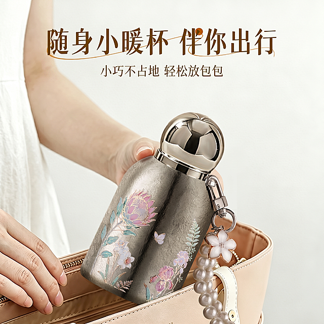 [主图 4] 纯钛口袋保温杯小巧便携场景展示。氛围风格：清新雅致治愈风，日常出行氛围感。画质：商业摄影质感，光线柔和通透，产品清晰真实，画面干净高级。元素：展示纯钛口袋保温杯轻松放入女士手提包中的场景，一只手正在将保温杯放入包中，包为浅米色百搭款式，背景为干净浅灰色。保持产品外观与输入产品图绝对一致，杜绝变形色差，精准还原大小比例。商品主体占比约60%。光影：柔和室内自然光，整体明亮干净，阴影柔和。配色：主色调浅米色、浅灰色，搭配产品银色，清新雅致。视角构图：平视场景构图，自然真实。文字版式：顶部大标题「随身小暖杯 伴你出行」深棕色粗体，副标题「小巧不占地 轻松放包包」浅棕色小字，均在上方留白区域，不遮挡产品核心展示。比例分辨率：1:1比例，2k分辨率；文字清晰，画面超高清。负向提示词：变形，水印，文字错乱，产品模糊，背景杂乱。