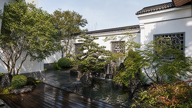 将这张中式园林景观模型图转换为真实实景照片效果，保留原构图和场景，生成自然真实的实景摄影效果，真实的植物和石材纹理，自然光影质感。