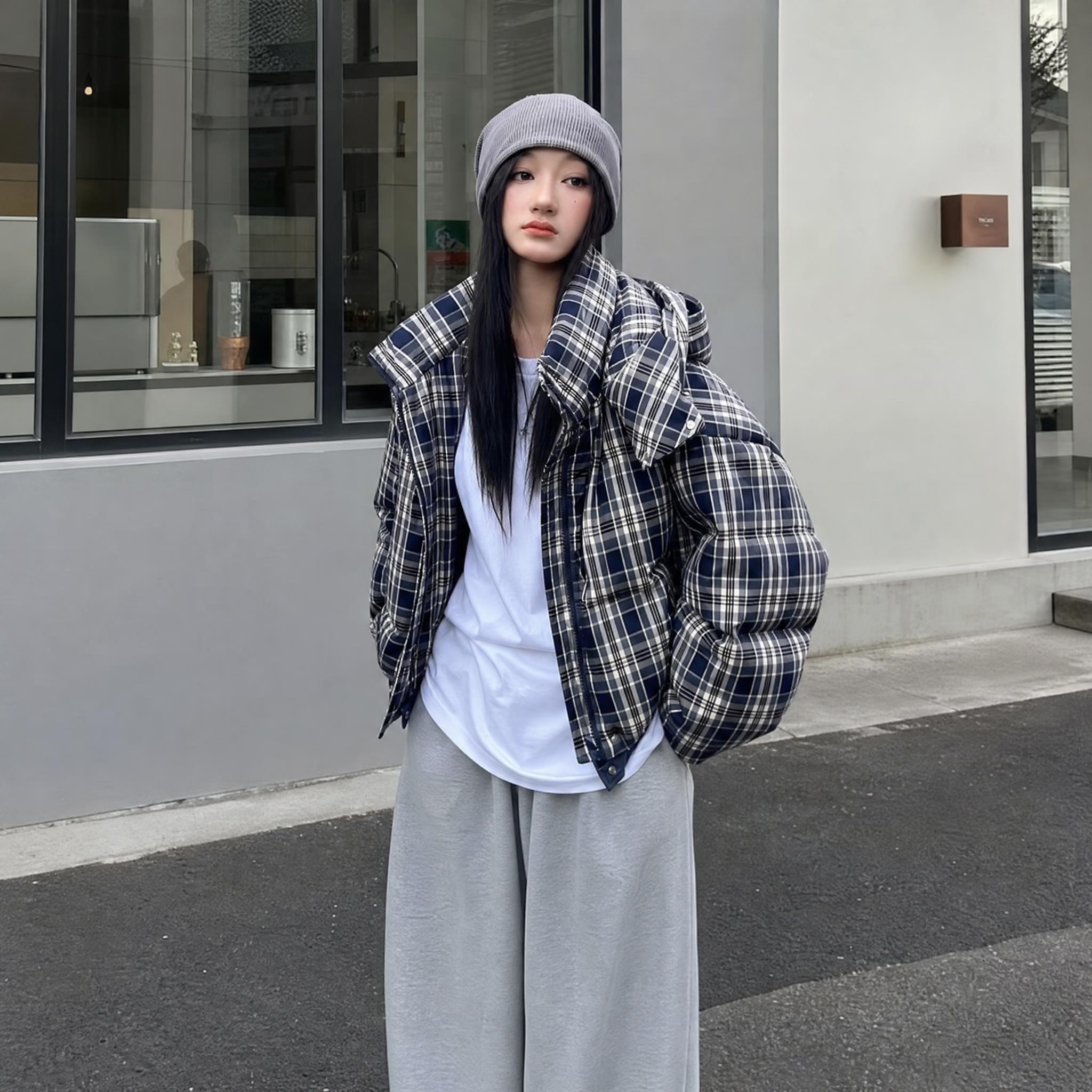 欧美年轻女模特身穿藏青色底米白格纹短款连帽羽绒服，正面站立于极… - 图片创意预览