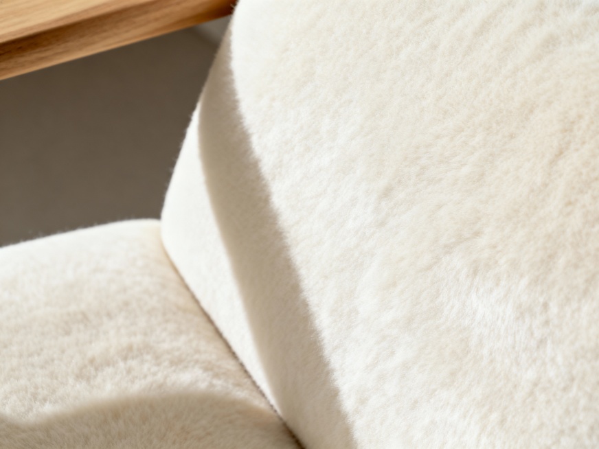 特写镜头，奶油白色毛绒软垫家具的一角，质地柔软顺滑，柔和光线照射，营造干净、极简、舒适的氛围，左上角有一丝木质细节预览效果