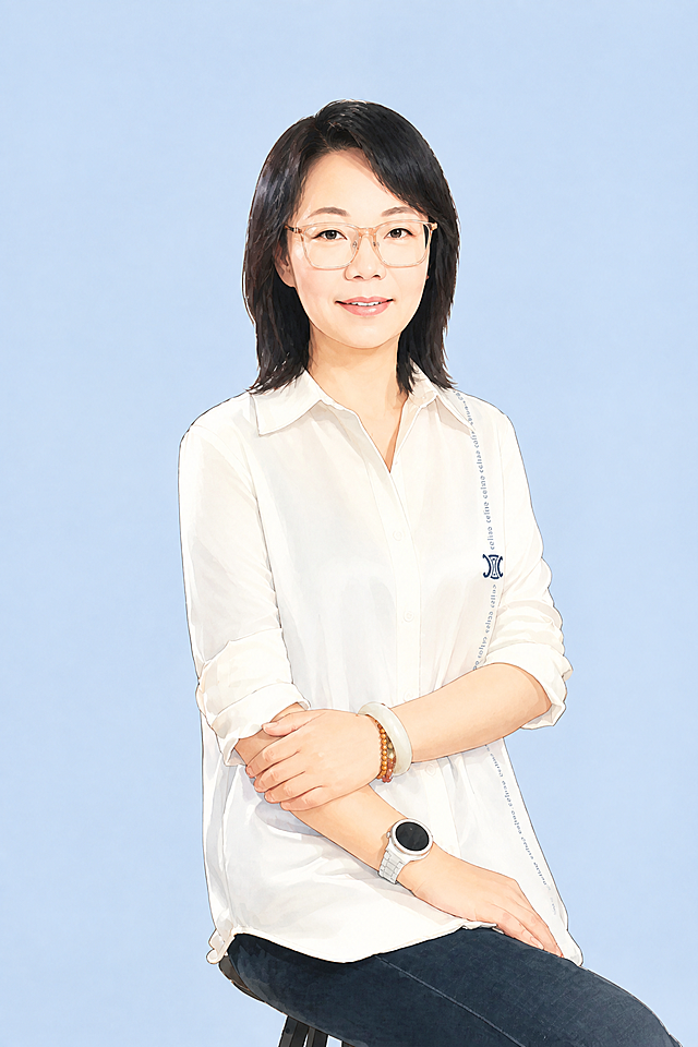 参考图中中年女性的五官特征、黑色齐肩短发发型、脸型、成熟亲和的气质，保留白色翻领衬衫的大体服装风格，保持原照片坐姿和双臂交叉的姿势动作，不额外增加手持道具。生成单人半身卡通形象，柔和半扁平插画风，轻水彩质感，线条干净细腻，表情自然亲和，职场感，正式、温暖、年轻但不幼稚。背景为浅蓝色纯色背景，画面简洁高级，无复杂装饰，适合企业周年庆电子贺卡人物形象。不要增加蛋糕、横幅、鲜花、卡片等任何道具；不要改变原照片动作；不要改变性别；不要过度美颜；不要低龄化；不要性感化；不要奇怪手指；不要畸形手部；不要多人；不要复杂杂乱背景；不要水印；不要AI生成字样；不要品牌/IP风格。