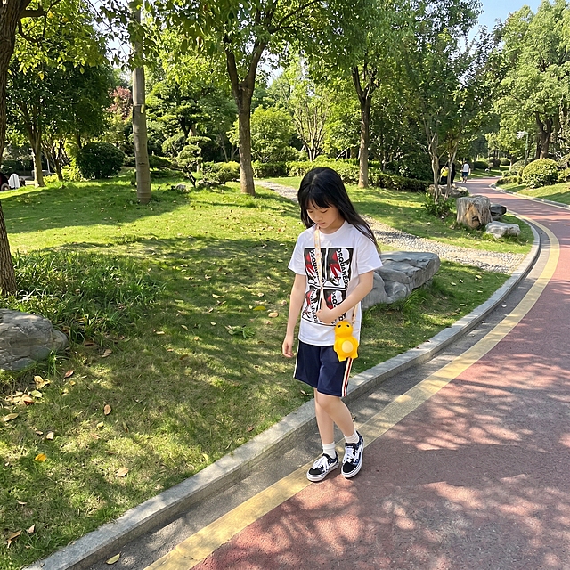 扩充图片周围的环境，保留原图人物和物品，延续公园草坪步道的户外自然场景