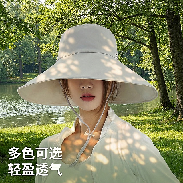 保持原图中浅灰色防晒帽和模特、服装的样子不变，将背景替换为户外自然场景：包含绿色草地、树木、平静水面，阳光透过树叶洒下斑驳光影，整体氛围清新自然，突出夏日防晒的场景感。展示大帽檐正面遮阳效果，保持帽子和模特细节不变，风格统一和前面主图一致。左下角添加文字"多色可选 轻盈透气"，字体为白色无衬线粗体，不要遮挡帽子和模特面部。