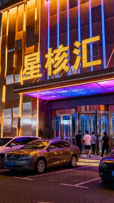夜晚城市里的商务KTV门头，招牌是巨大的金色发光字体 “星核汇”，门头装饰有暖黄色 + 蓝紫色渐变霓虹灯光，建筑外立面是金属质感的装饰面板，门口停着几辆轿车，有几位顾客进出，整体氛围奢华亮眼，金属质感预览效果
