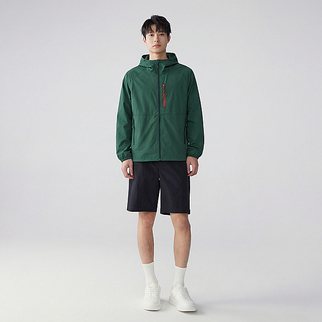 参考原模特姿势动作，重新生成图片，墨绿色带帽连帽外套完全贴合模特身形，保留衣服原有版型、墨绿色颜色、红色拉链细节、黑色口袋拉链细节，无变形，无颜色偏差，保留所有细节。背景保留灰色地面与浅白色背景，光线自然，写实风格，8k，高细节，对焦清晰，无变形