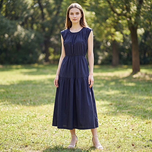 将这件藏青色无袖连衣裙穿在一个乌克兰模特身上，模特五官精致立体，身高168cm身材比例修长，纤瘦唯美，保持服装原有颜色、长短比例不变，严格保留服装款式，穿着及动作自然，符合衣服风格。背景为大自然户外公园草地风光远景，构图2250*2250正方形，人物居中，采用远深景视角完整展现全身穿搭，搭配2026年流行浅色系夏季有跟鞋子。丁达尔光，高调布光，减少阴影，光线均匀，无硬阴影，干净专业的户外摄影背景，背景中性不抢镜。整体氛围立体明亮，优雅氛围感，时尚穿搭写真风格，质感细腻