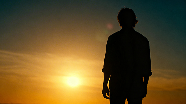 一个人坚定站立面对落日，多个柔和阴影向不同方向延伸，黄金时刻光线，融合与希望的隐喻图像，电影风格，写实风格