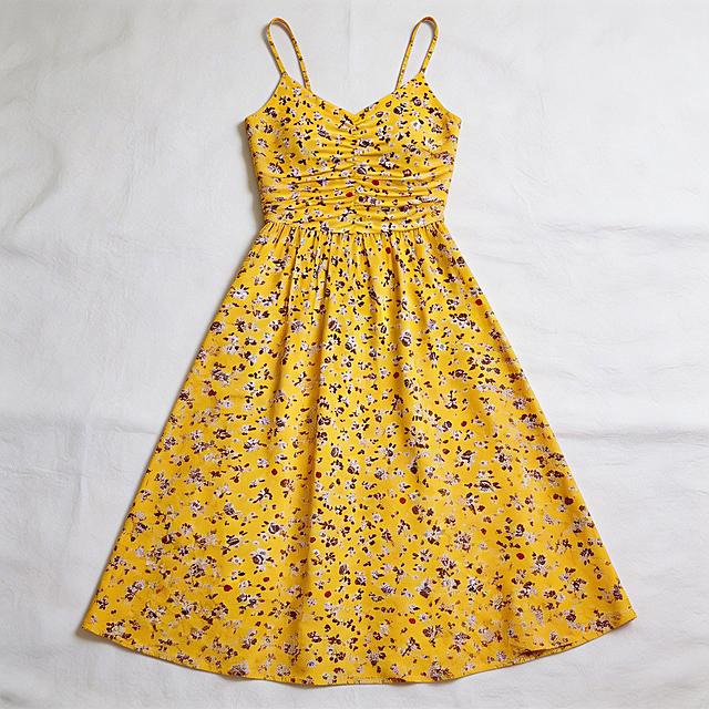 将这条黄色碎花吊带裙平铺展开，生成一张自然平整的服装平铺展示图，保留原有的黄色底碎花图案和款式
