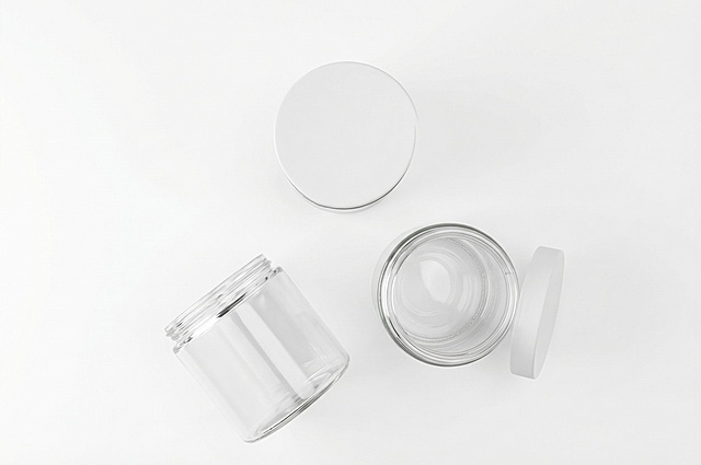 产品精修，清除所有指纹、灰尘与瑕疵，让产品看起来崭新；精准还原白色圆盖透明玻璃罐的颜色与包装材质：玻璃通透、塑料哑光；增强瓶身光影立体感，提升整体质感和高级感，瓶身标签/文字清晰锐利，光线柔和均匀，突出产品精致感，符合电商主图标准，放置于纯净的纯白背景，正视图平视视角，3D渲染效果