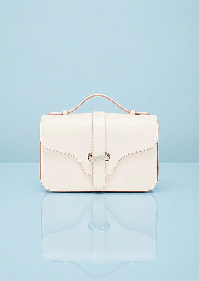 将这款米白色手提包放在高反光的浅蓝色平面上，保留包的原有细节和颜色，背景为浅蓝色调，包在平面上有清晰的倒影，不要花岗岩材质，高度还原包的形态和配色