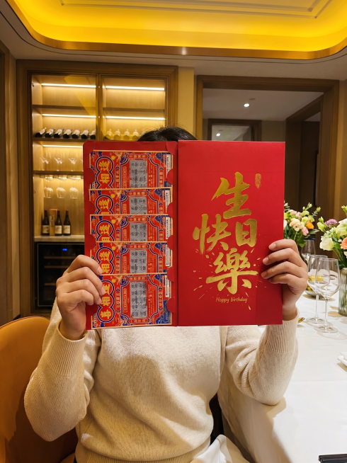 完全保留原图的构图比例，视角为日常手机拍摄的平视角度，无夸张透视，画面层次自然，完全保留人物姿势，拿东西的姿势，原红包的排版、数量、设计、尺寸，禁止改变排列样式，必须左右并排；将背景改为高端精致的西餐预览效果