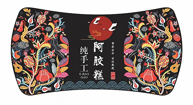 将第一张阿胶糕铁盒包装的国风插画设计，重新排版适配第二张图所示的腰形（两端圆弧、上下边向内凹的长条形贴纸）形状。保留原设计的核心元素：左右两侧的国风花鸟植物纹样（石榴、花朵、鸟、祥云），中间黑色区域的红色圆月、仙鹤、"阿胶糕 纯手工"书法字体、"秉承古方 古法熬制"竖排小字、"珍品"红色印章、底部水波纹。重新调整细节布局，使图案在腰形贴纸内美观协调，左右对称，颜色对比鲜明，纹样细节精致清晰，整体为国潮国风风格，适合做不干胶贴纸，边缘干净无多余背景