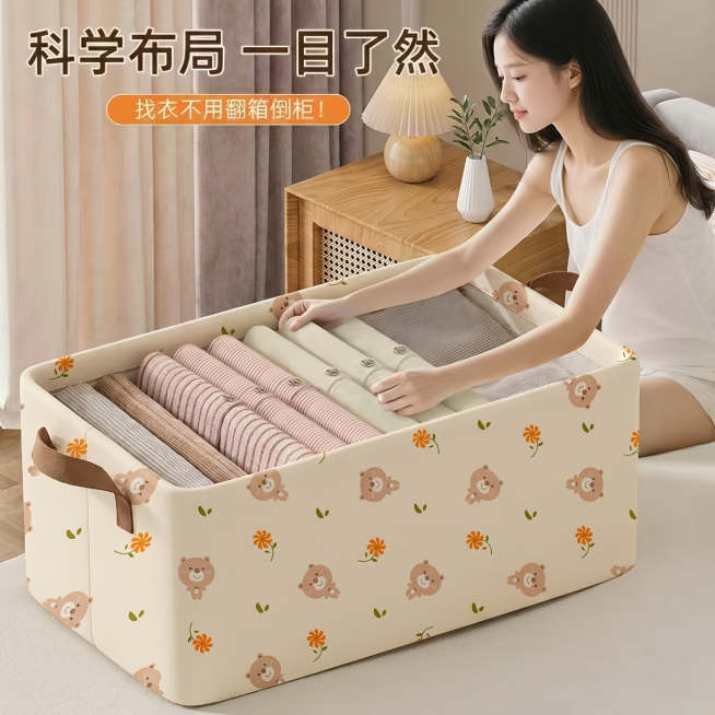 将画面中原收纳箱替换为第二张图的小熊花朵图案收纳箱，收纳箱摆在床铺上，保留模特整理衣物的动作，保留背景的木质床头柜、窗帘等所有元素不变，整体风格自然融合，真实温馨有生活感预览效果