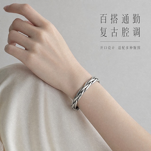 [主图-3] 复古做旧编织银手镯 佩戴效果展示 突出上身效果与百搭气质
[统一基调] 高级复古银饰风格 背景为浅灰色哑光岩板台面搭配米白色真丝布料 整体冷调柔光 字体使用纤细文艺衬线体 主标题字色深银灰 辅助字色中灰 强调色哑光银 无厚重色块 极简克制
[画面] 女性手模手腕特写 手模肤色白皙 手腕纤细 佩戴着这款编织银手镯 手镯位于手腕正中 开口朝内侧 展示佩戴后的贴合度和大小比例 手模自然放松 手指微曲 手腕下方衬着米白色真丝布料 背景为浅灰色纯色 简洁干净 突出手镯佩戴效果 手镯的哑光做旧银色与白皙肤色形成柔和对比 编织纹理在手腕上呈现自然弧度 整体氛围优雅复古 有质感
[光影质感] 自然光感人像特写质感 柔光从侧上方打来 手腕皮肤有自然的明暗过渡 手镯金属有柔和高光和阴影 接触皮肤处有自然阴影 真实不悬浮
[配色] 背景浅灰 皮肤自然白皙 手镯哑光银 文字深银灰 整体柔和高级
[文字版式] 画面右侧竖排或右上方横排主标题 "百搭通勤 复古腔调" 下方小字 "开口设计 适配多种腕围" 字体纤细文艺 不遮挡手部和手镯主体
[输出要求] 1:1正方形比例 文字清晰锐利 手镯佩戴自然真实 手部形态正常无畸形 无穿模 无错字 无模糊 无水印 无平台Logo