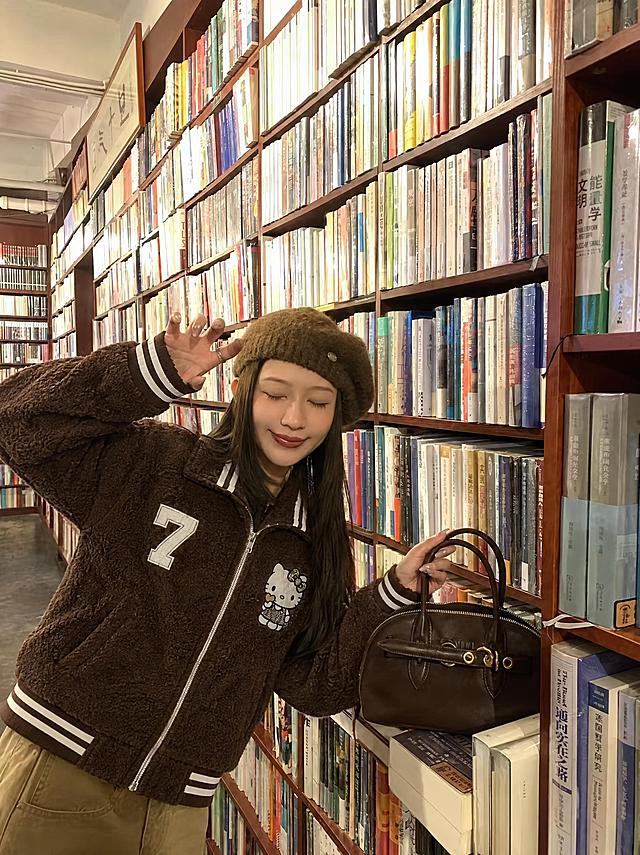 将图1中的棕色羊羔毛翻领棒球服外套穿到图4模特身上，衣服版型、花色、纹理、面料严格复刻参考服装，左胸白色数字7刺绣、右胸Hello Kitty图案、袖子白色条纹、领口袖口下摆的白棕条纹罗纹边全部精准还原。真实人像摄影，自然光，皮肤质感真实，高清，写实，柔和环境光影，衣服贴合身体，服装褶皱自然，无水印，无文字，无logo，无畸形肢体，画面干净，不要改变人物长相，保留模特原有姿势、帽子、下装、手提包和背景环境不变