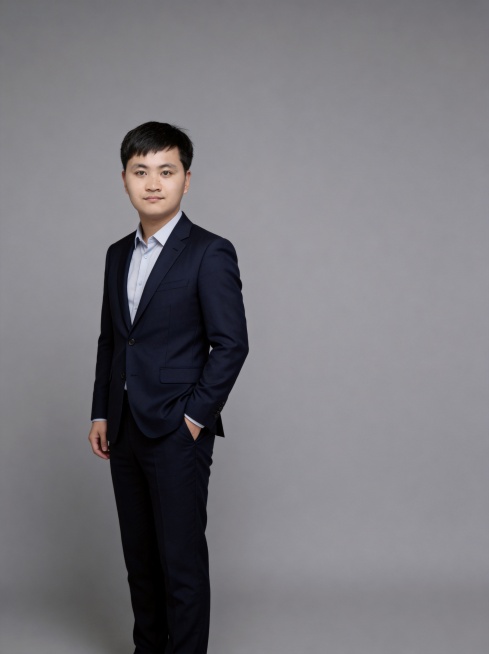 参考这张图片，生成专业的律师职场形象照，保留人物脸型发型年龄特征，穿着藏青色正装西装外套搭配素色衬衫和西裤，左手插兜自然站姿，灰色纯色背景，专业严谨气质，3:4比例，高清细节预览效果